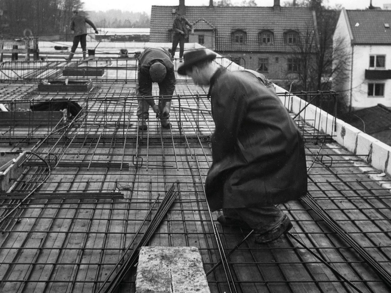 Mannen met jaren 50 hoeden en jassen aan het werk op een bouwlocatie.